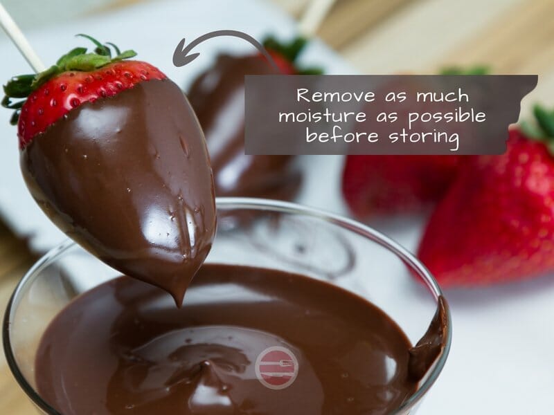 strawberry being dipped into chocolate